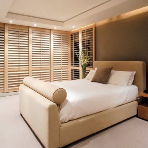 Sliding stained timber shutters in bedroom